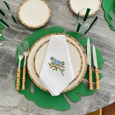 Mesa posta com louça e talheres com tema bambu e guardanapo com papagaio bordado