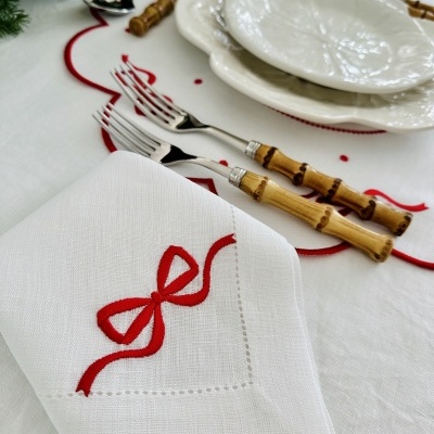 Conjunto de talheres de madeira, pratos brancos com relevo, guardanapo com bordado vermelho