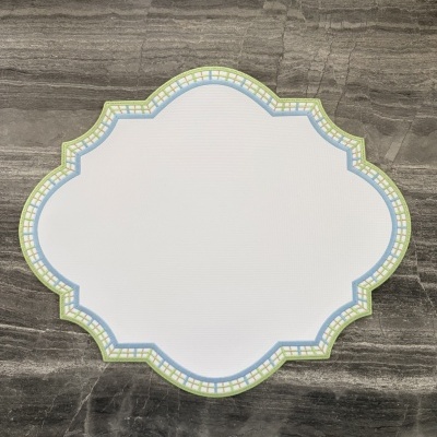 Jogo americano branco com borda quadriculada azul e verde sobre pedra cinzenta