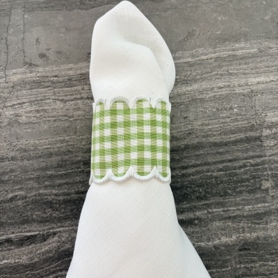 Guardanapo branco com argola verde quadriculada em superfície cinza