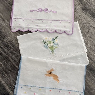 Toalhas brancas bordadas com laços, flores e coelho em tons pastel