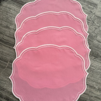 Conjunto de bases de mesa rosa com bordas brancas sobre chão cinzento