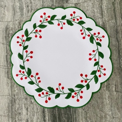 Guardanapo branco com borda verde e padrão de folhas verdes e bagas vermelhas.