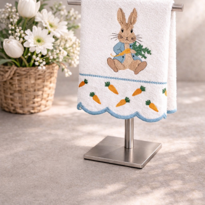Toalha branca com bordado de coelho e cenouras num suporte metálico
