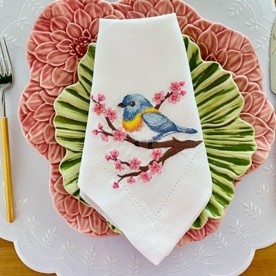 Conjunto de pratos coloridos com guardanapo bordado com pássaro azul e amarelo