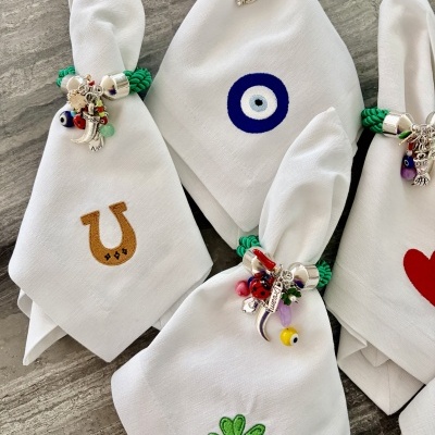 Guardanapos de pano brancos com bordados coloridos e argolas com pendentes