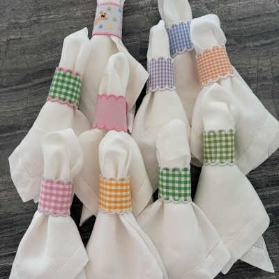 Guardanapos brancos com argolas xadrez e coloridas sobre superfície cinzenta