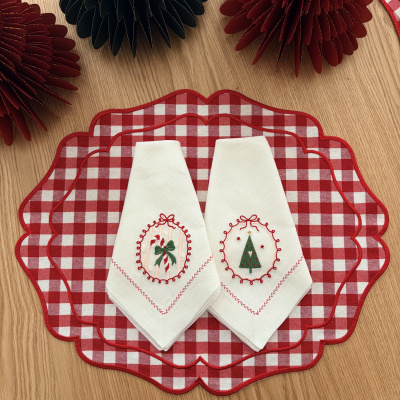bases de mesa xadrez vermelha e branca com dois guardanapos brancos bordados e decoração em papel