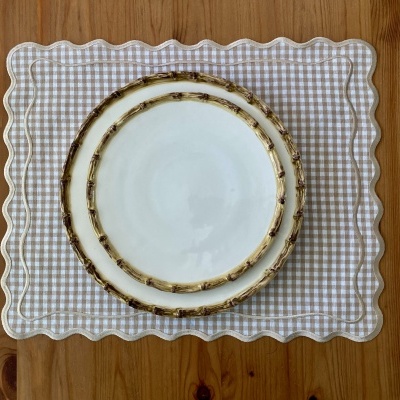 dois pratos brancos com bordas de padrão de ramos sobre base xadrez bege e branca com bordas onduladas