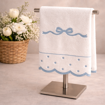 Toalha branca com bordado azul pendurada em suporte metálico e cesto de flores ao lado