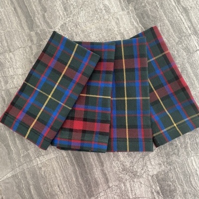 Saia plissada com padrão xadrez colorido sobre chão de azulejos cinzentos