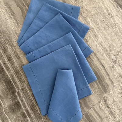 Guardanapos de tecido azul com borda decorativa sobre mesa de pedra cinzenta