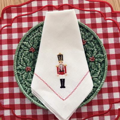 Individuais xadrez vermelho e branco, prato verde decorativo e guardanapo branco com soldadinho bordado