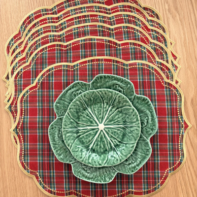 Bases de prato tartan e pratos decorativos verdes com forma de folhas sobre mesa de madeira.