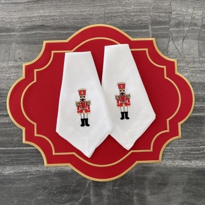 Dois guardanapos brancos com soldados bordados em suporte vermelho com dourado