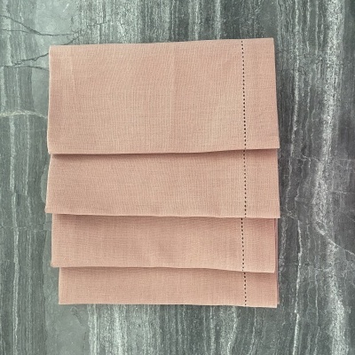 Guardanapo rosa claro dobrado em três sobre superfície cinza marmoreada