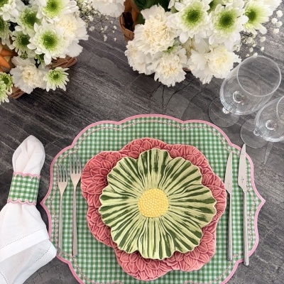 Conjunto de louça decorativa floral sobre base xadrez com talheres e guarda-napo à mesa