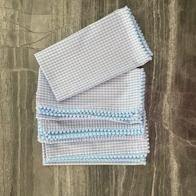 Paninhos xadrez branco e azul com bordado azul sobre mesa de madeira escura