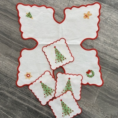 Toalha branca de Natal com bordas vermelhas e motivos bordados sobre superfície de pedra cinzenta