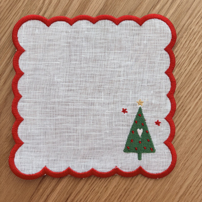 Pano branco com borda vermelha ondulada e bordado de árvore de Natal verde.