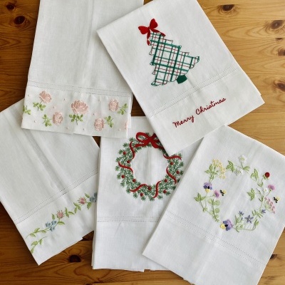 Cinco toalhas brancas bordadas com motivos florais e Natal
