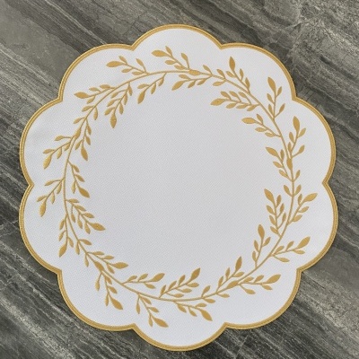 Colher de mesa branca com padrão dourado sobre superfície de pedra cinzenta