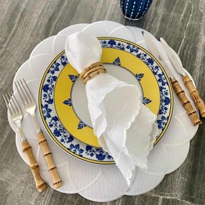 Conjunto de pratos, guardanapo, talheres e copo sobre mesa cinza marmoreada