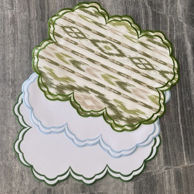 Quatro toalhetes com bordas onduladas e padrão têxtil sobre superfície cinza