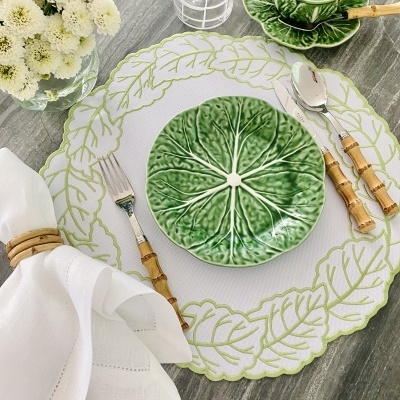 Mesa posta com prato, chávena e talheres com detalhes em folha e bambu