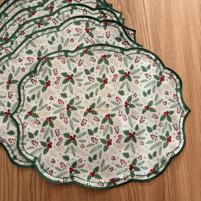 Individuais de mesa com padrão natalício de bagas e folhas, bordas verdes, sobre madeira clara.