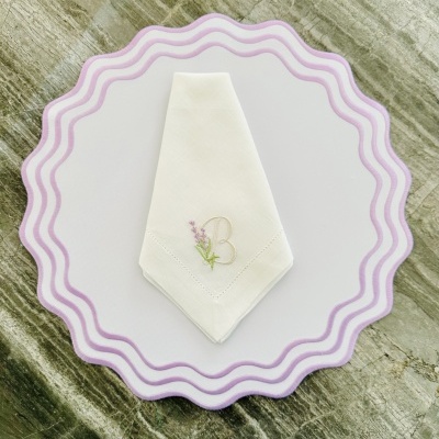 Guardanapo branco bordado com letra B e flor lilás sobre base branca com borda lilás