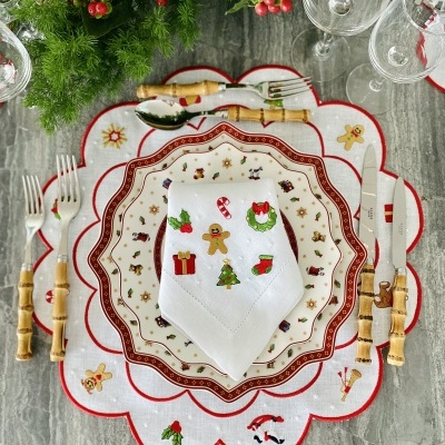 Conjunto de mesa natalício com guardanapo bordado, pratos decorados e talheres com cabos de bambu.