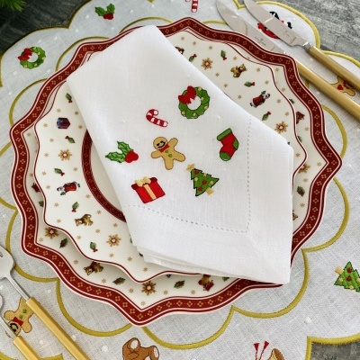 Conjunto de mesa com pratos, guardanapo natalício e talheres sobre toalha de mesa decorada
