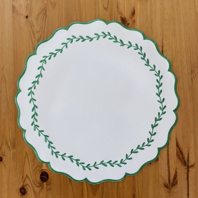 Porta-copo branco com borda verde e padrão de ramo verde sobre madeira clara