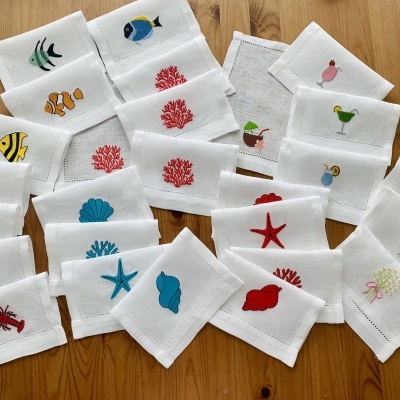 Tecidos brancos com bordados coloridos de vida marinha sobre madeira clara