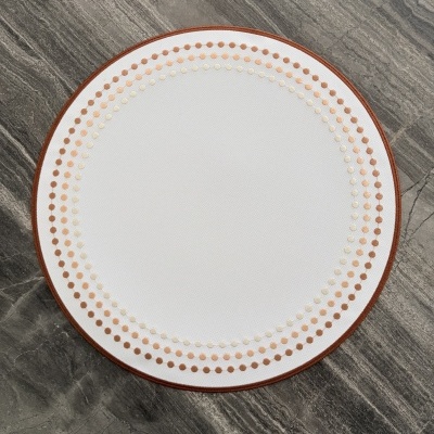 Tapete redondo branco com padrão de círculos castanhos sobre chão de pedra cinzenta