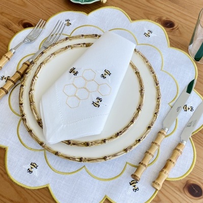 Conjunto de jantar com prato branco decorado, talheres com cabo em bambu, guardanapo e pega prato bordados com abelhas e favo de mel.