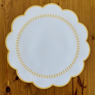 Toalhete branco com padrão dourado sobre madeira clara