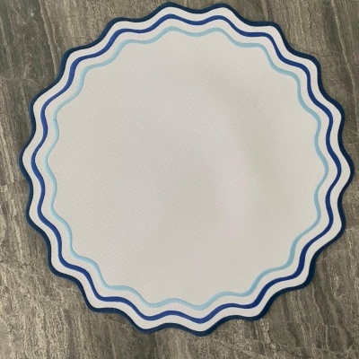 Tapete redondo azul com borda ondulada sobre piso de pedra cinzenta