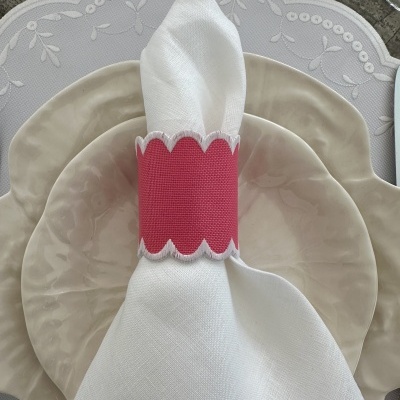 Conjunto de pratos e guardanapo com argola rosa sobre toalha branca bordada