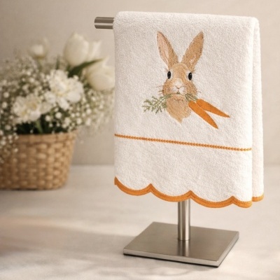 Toalha branca com bordado de coelho e cenouras em suporte metálico