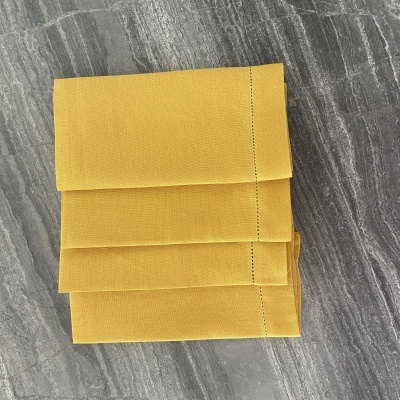 Guardanapo amarelo dobrado sobre superfície cinza marmoreada