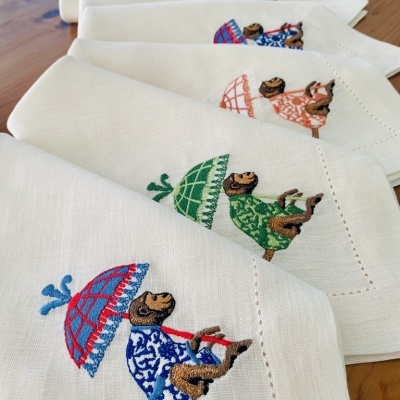 Guardanapos brancos com bordados de macacos coloridos e guarda-chuvas