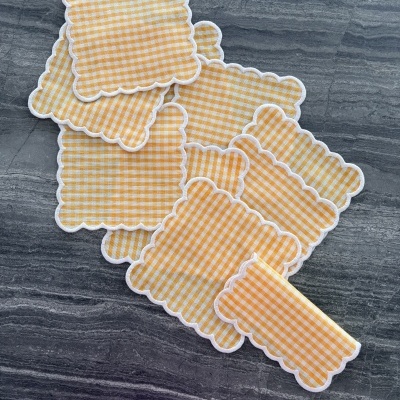 Guardanapos de tecido xadrez amarelo e branco com bordas onduladas brancas