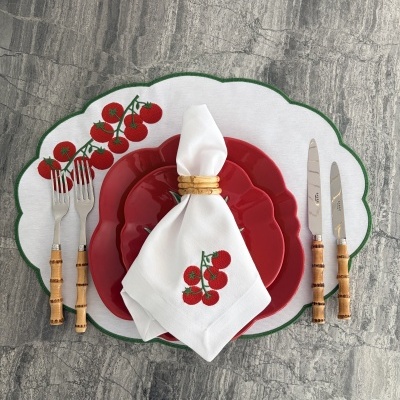 Mesa posta com pratos vermelhos e guardanapo branco com estampa de tomates