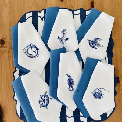 Guardanapos de tecido branco com bordados náuticos azuis sobre base azul e branca