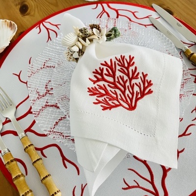 Conjunto de mesa com decoração vermelha de coral e talheres com cabos de bambu numa mesa de madeira