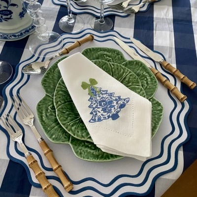 Mesa posta com pratos verdes texturizados, guardanapo bordado, talheres com cabo de bambu e toalha xadrez azul