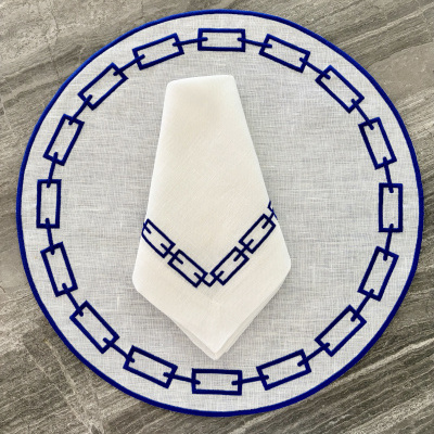 Jogo de mesa redondo com toalha branca e padrão azul geométrico sobre pedra cinza