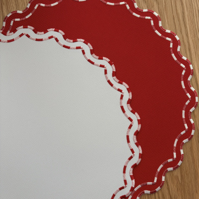 Dois jogos americanos de tecido vermelho e branco com bordas onduladas sobre madeira clara.